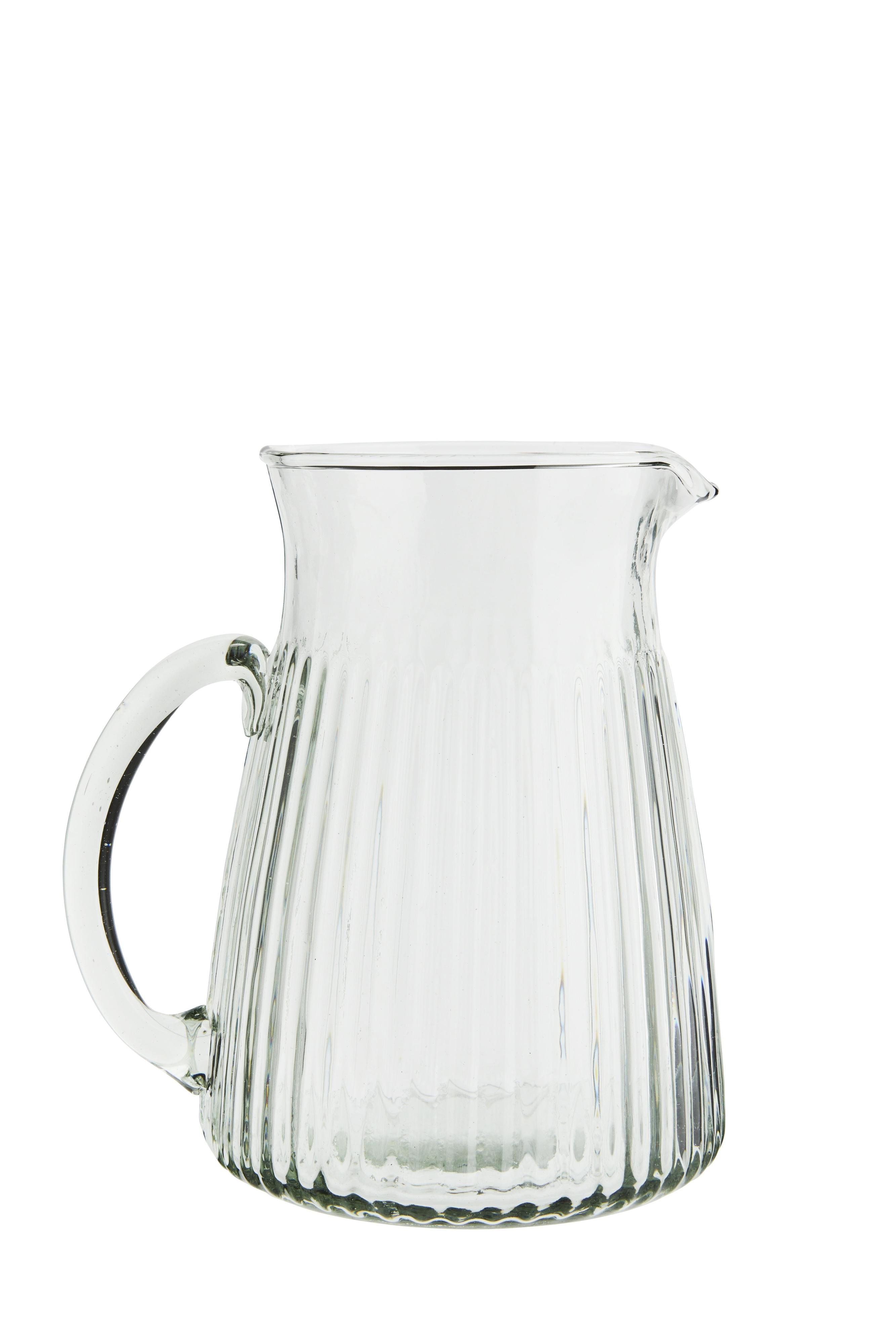 Clear glass pitcher with ribbed design on a white background