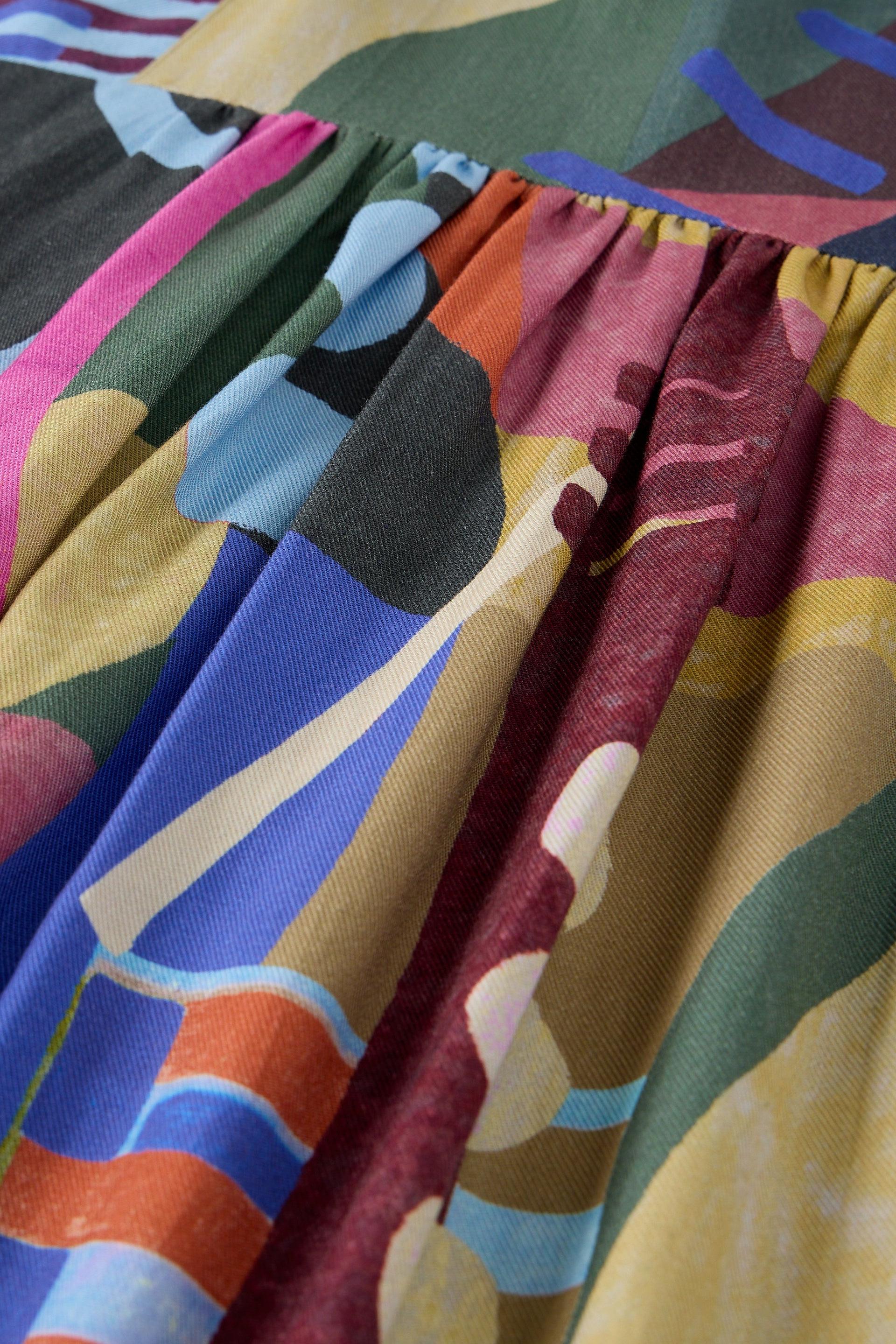 Close-up of pleated Ecovero fabric featuring a colorful abstract pattern with geometric shapes.