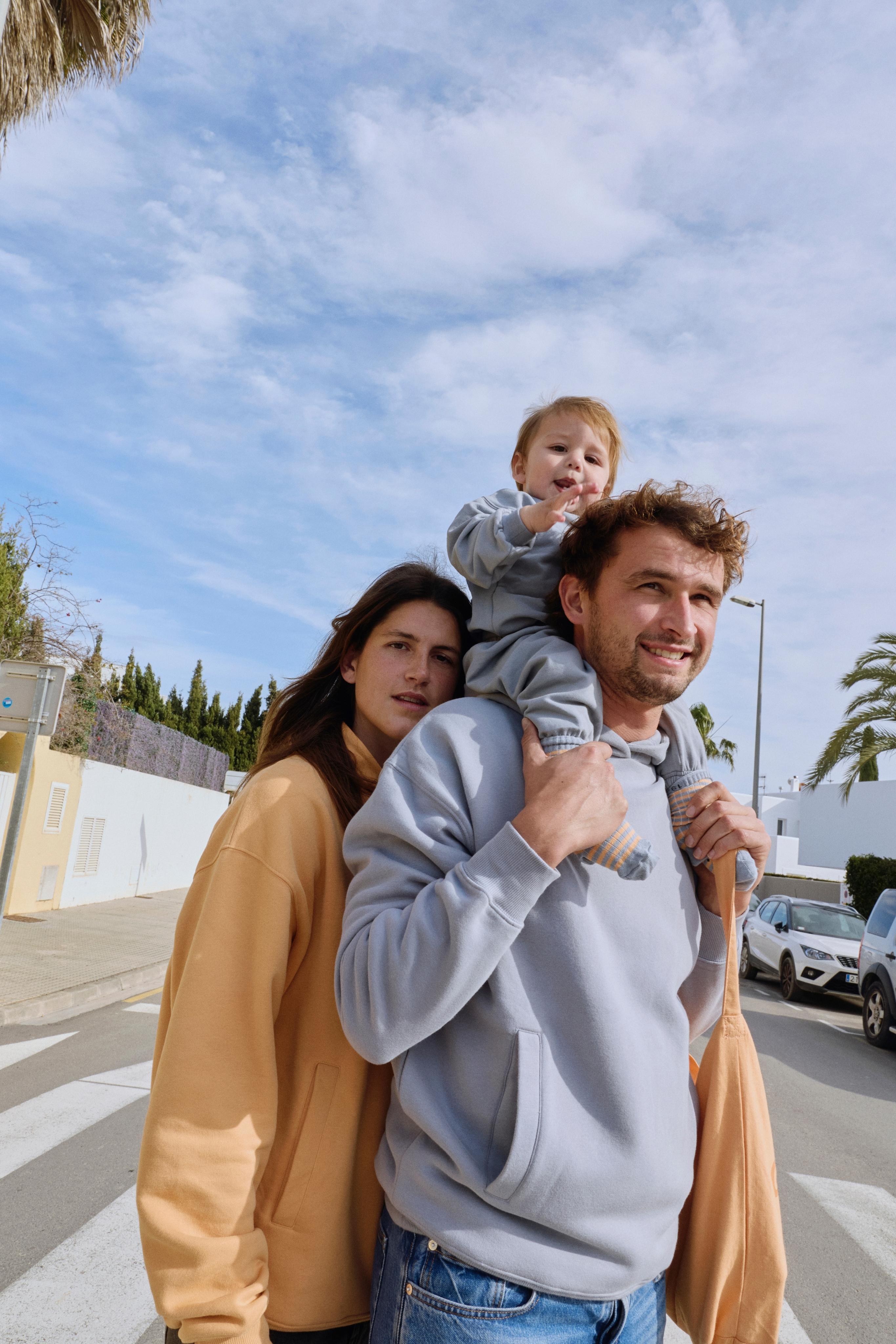 Family of three wearing Gray Label outdoors with a clear sky