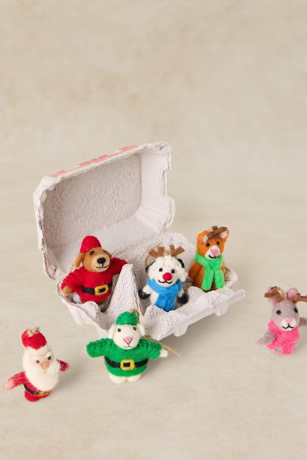 Set of handmade of decorations including Santa, reindeer, and snowman figures in an egg carton