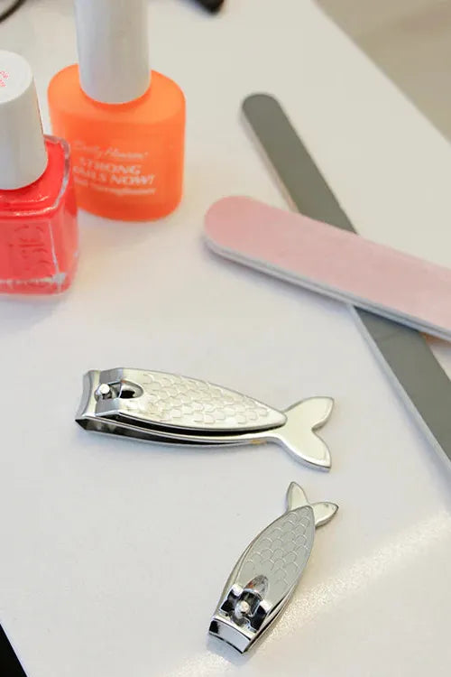 Nail care tools including nail clippers, a file, and nail polish on a white surface.