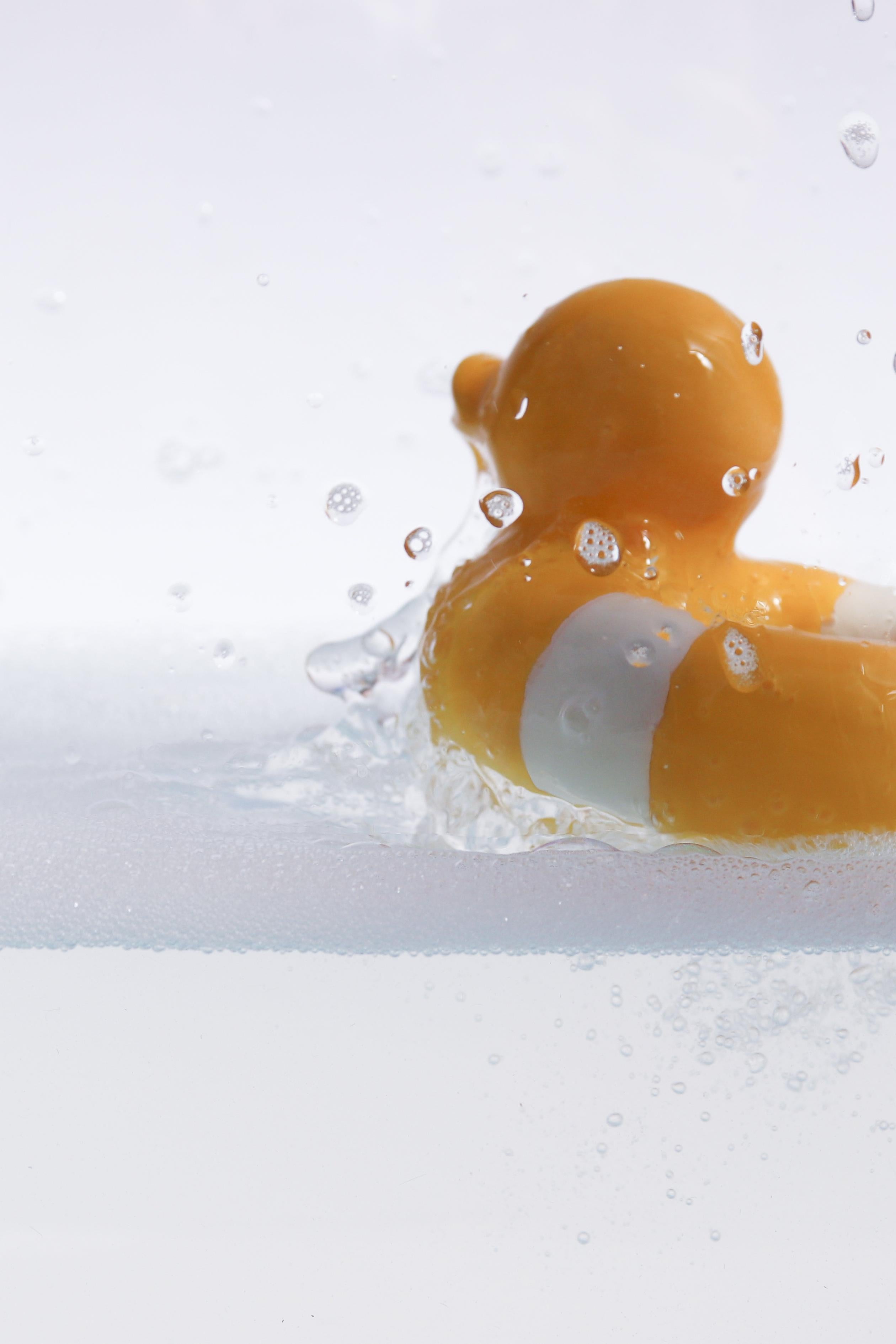 Flo the Floatie Yellow, natural rubber teether and bath toy splashing in water.