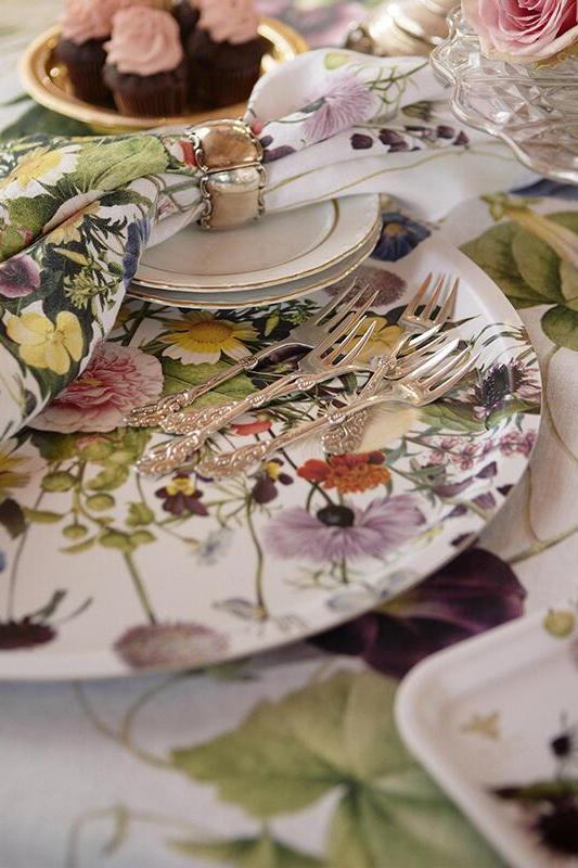 Floral table setting with plates, cutlery, and napkins on a matching tablecloth.