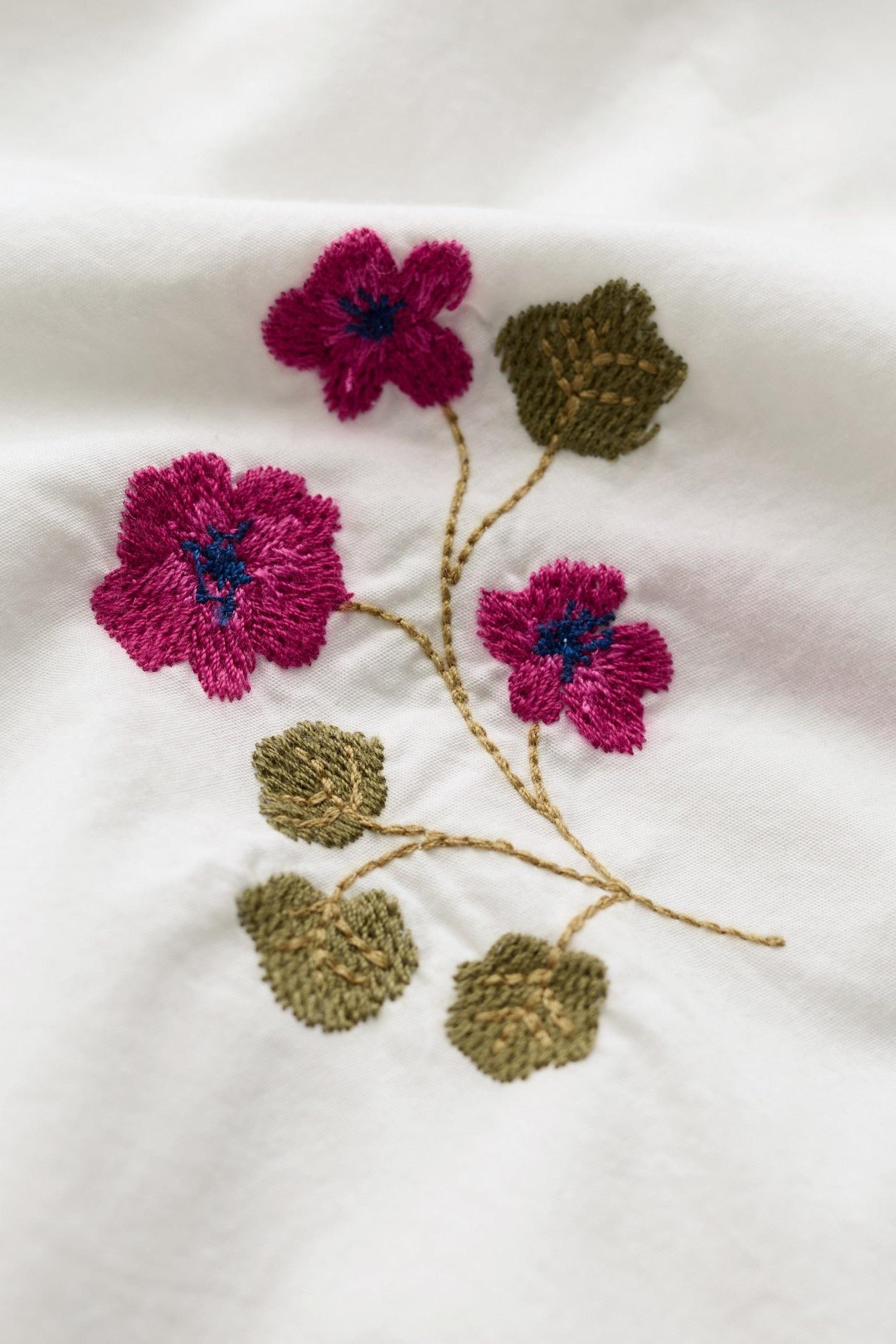 Embroidered flowers and leaves on a white fabric background