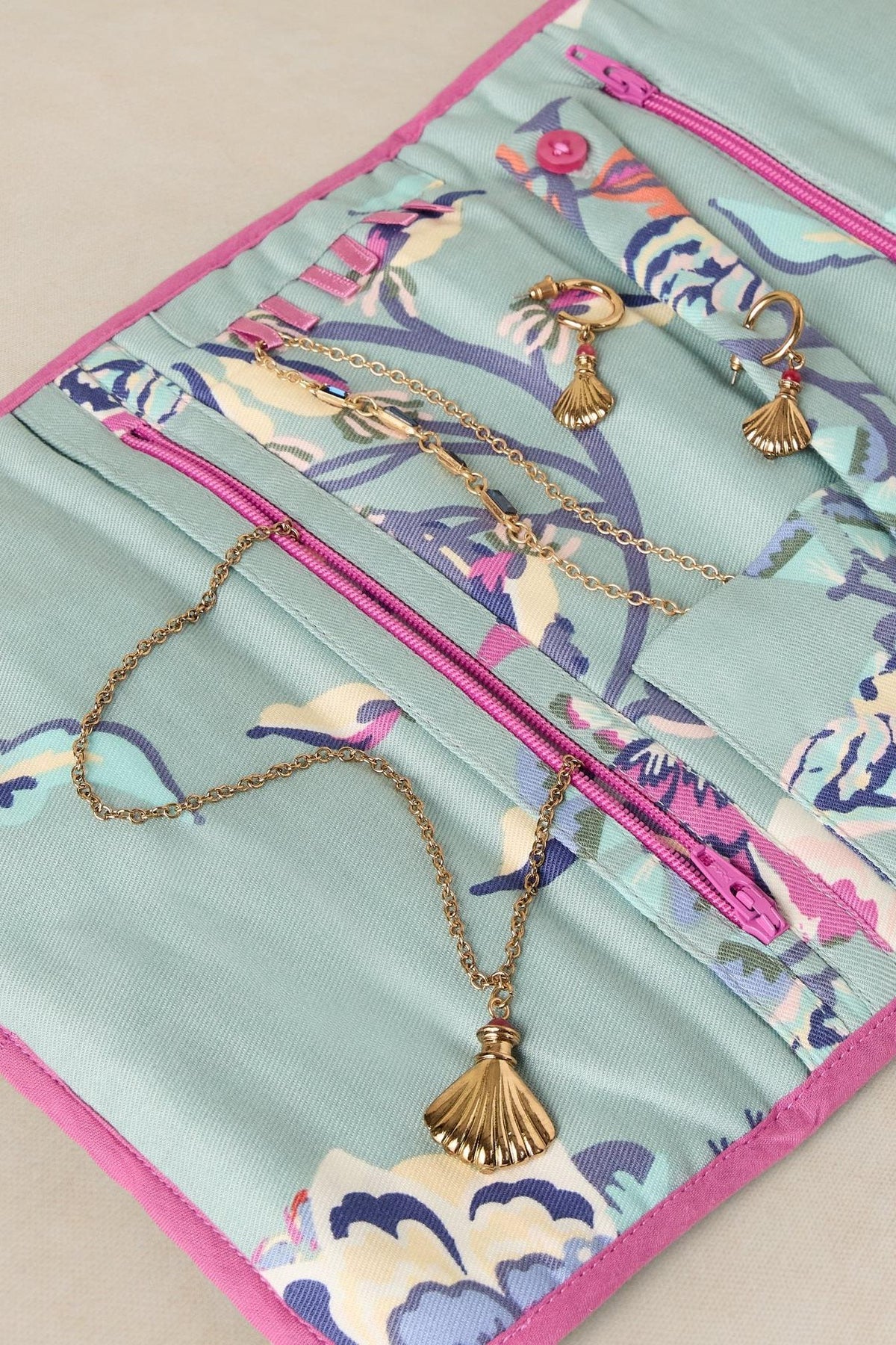 Open floral travel jewellery organiser pouch containing gold necklaces and earrings.