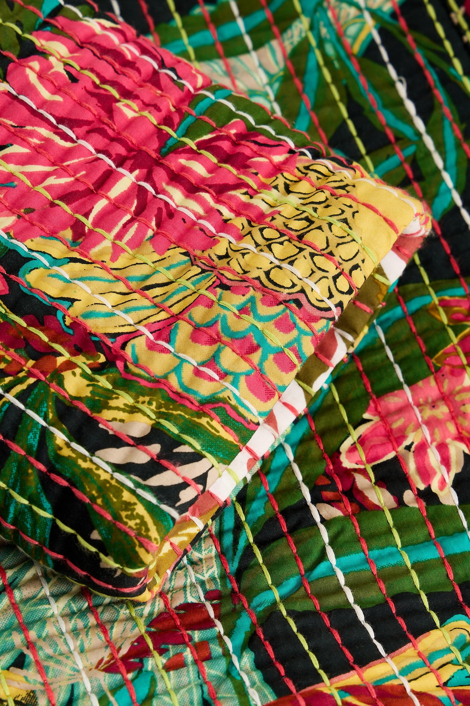 Close-up of a floral print kantha quilt made from soft organic cotton with hand-stitched details.