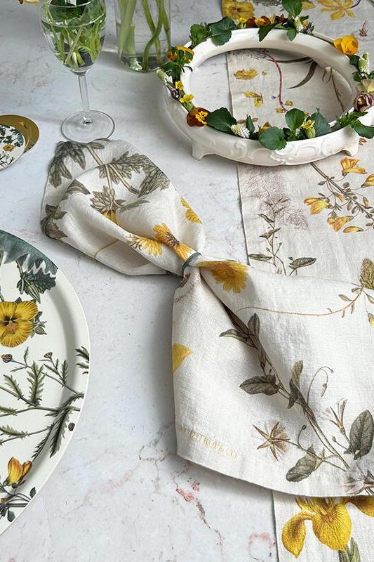 Table setting with floral plates, napkin, and placemat on a light surface.