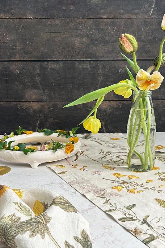 Table setting with floral decorations, including a vase of flowers and a wreath, on a wooden table.