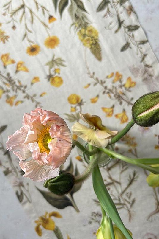 Pink flower and green bud on a floral-patterned fabric background