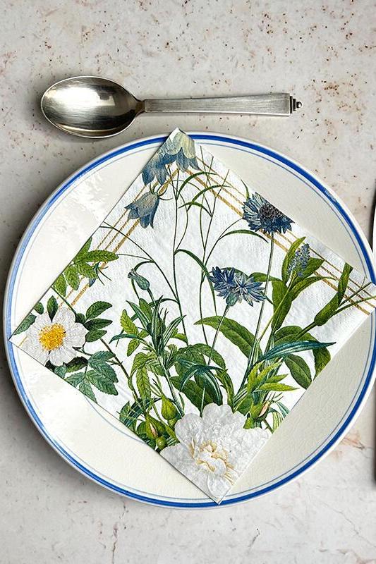Plate with floral design napkin on a marble surface with cutlery.