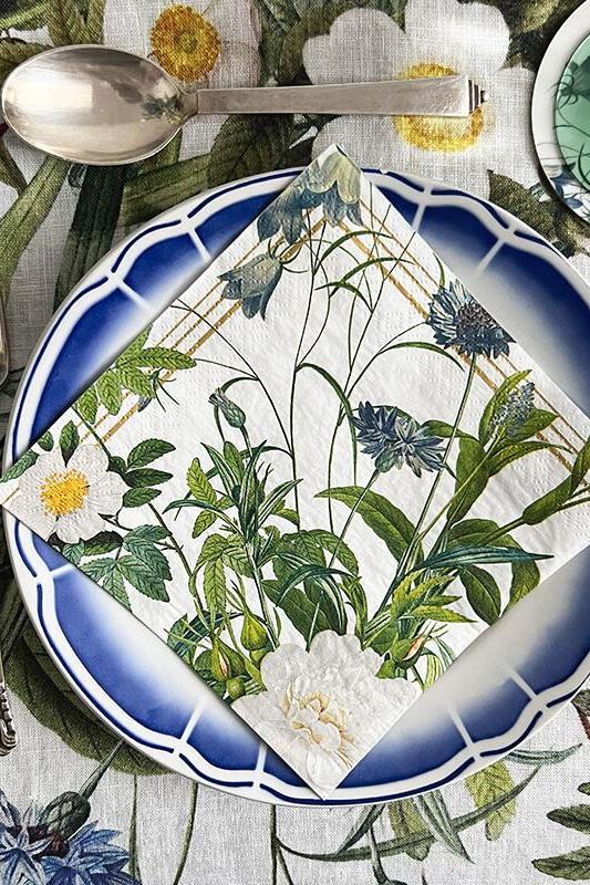 Table setting with floral-patterned napkins, cutlery, and a white tablecloth.