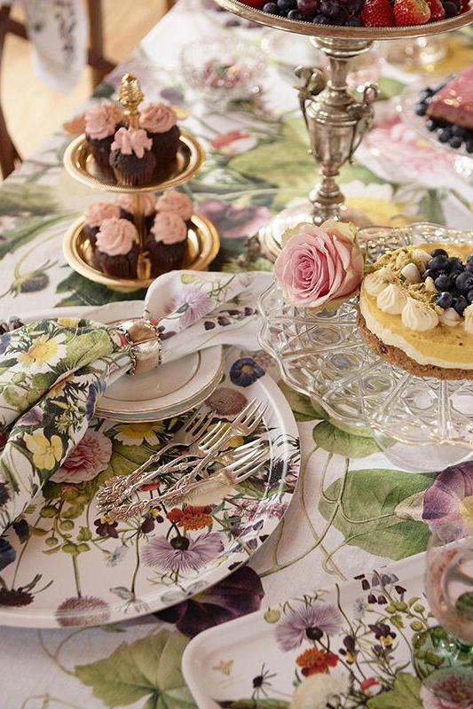 Decorative table setting with floral tablecloth, plates, and desserts.