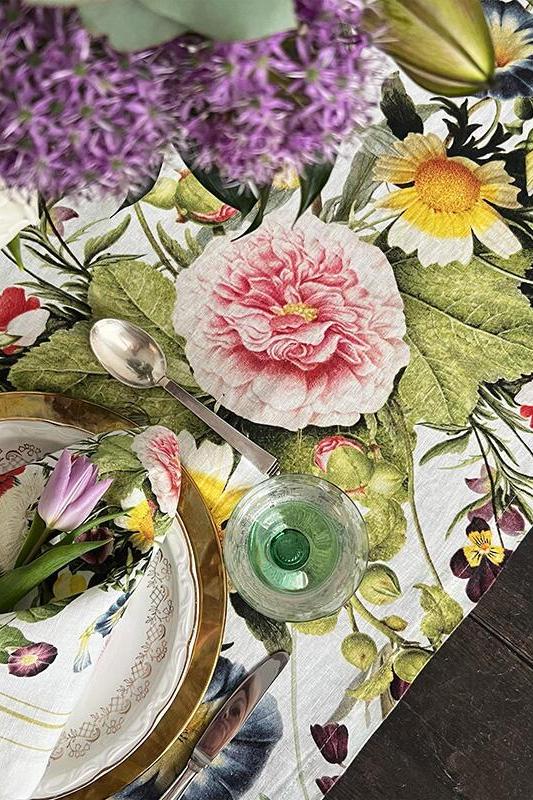 Table setting with floral tablecloth, plates, cutlery, and a glass.