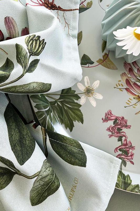Floral and botanical patterned fabric with a visible brand name on a neutral background