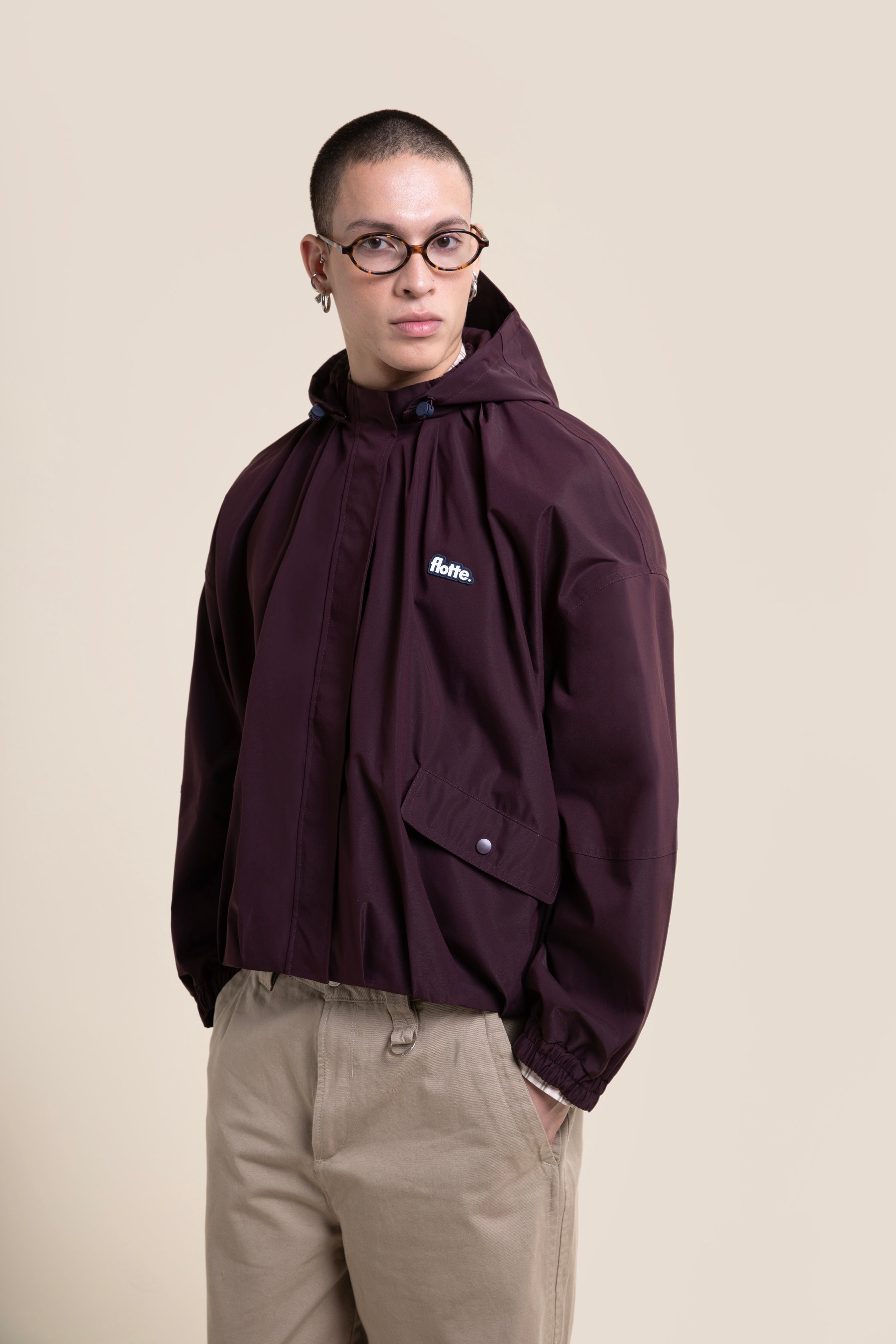 A man wearing a stylish deep purple Flotte waterproof coat made from recycled polyester.