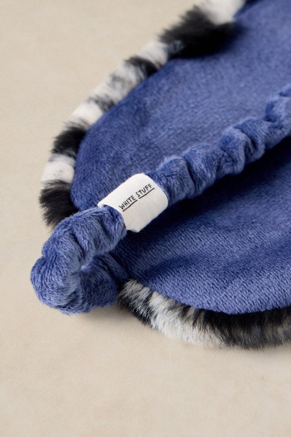 A soft blue sleeping mask with fluffy zebra print trim and White Stuff branding on a neutral background.