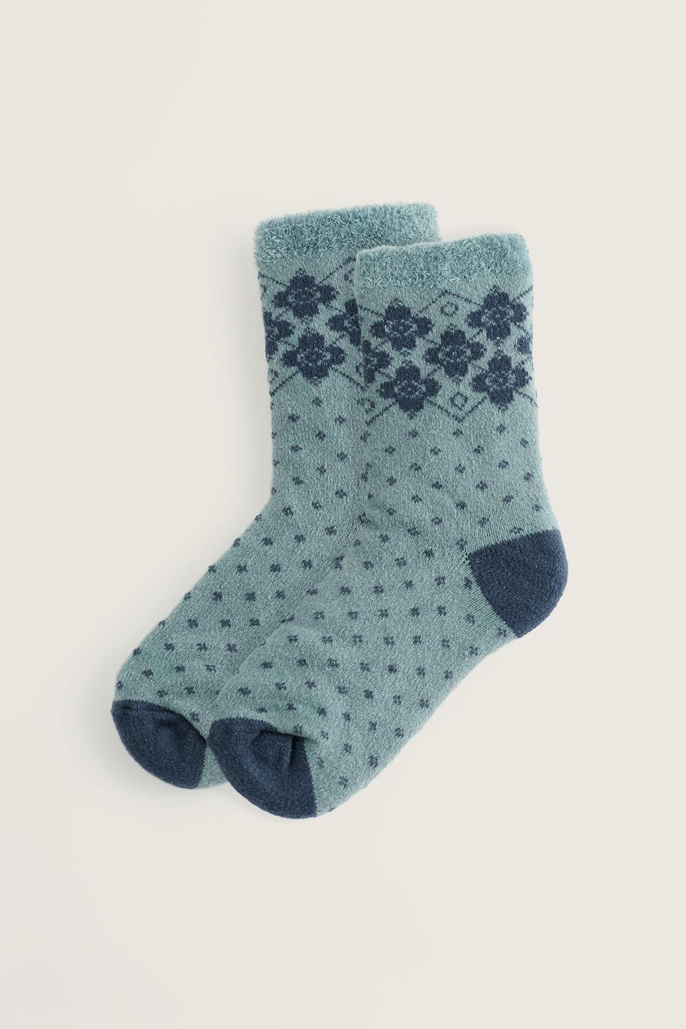 A pair of light blue fluffy winter socks with a navy blue floral pattern and solid navy toes and heels.