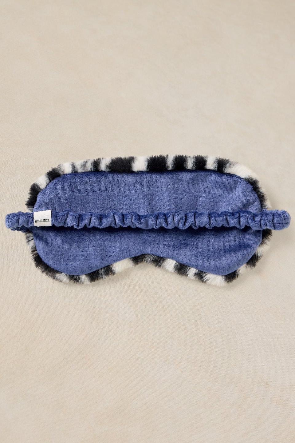 A soft, fluffy zebra print sleeping mask with a blue interior by White Stuff.