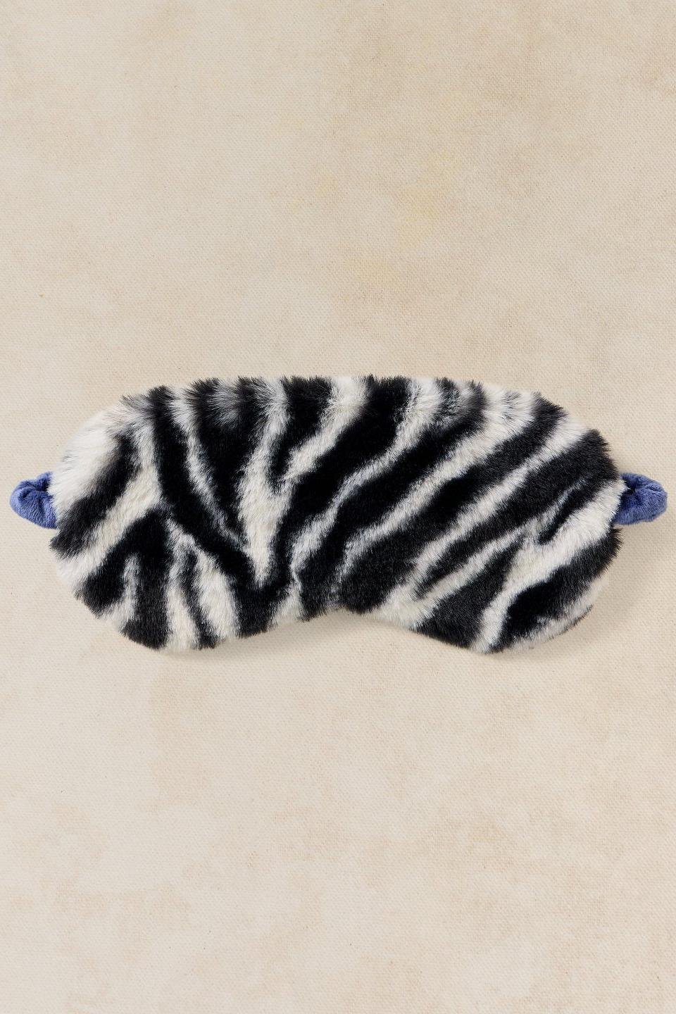 A soft and cosy zebra print fluffy eye mask on a neutral background.