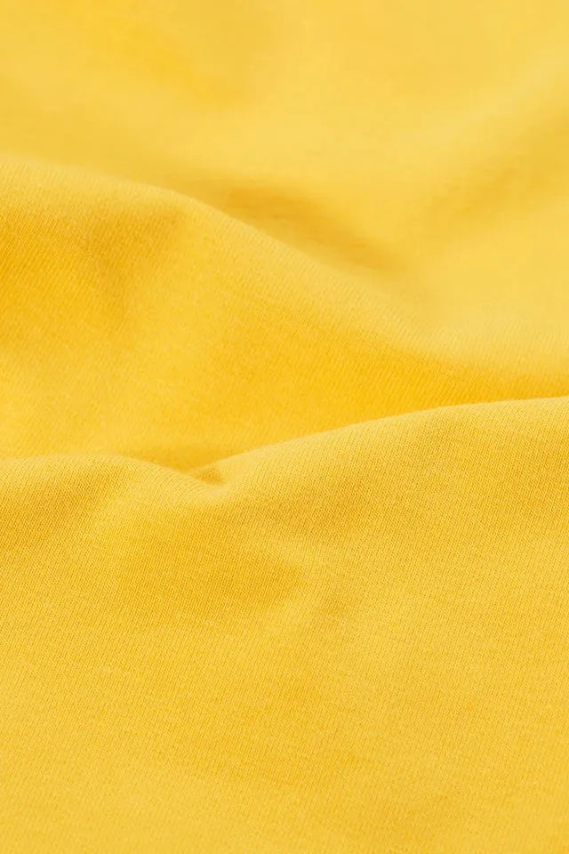 Close-up view of bright yellow organic cotton fabric texture for leggings.
