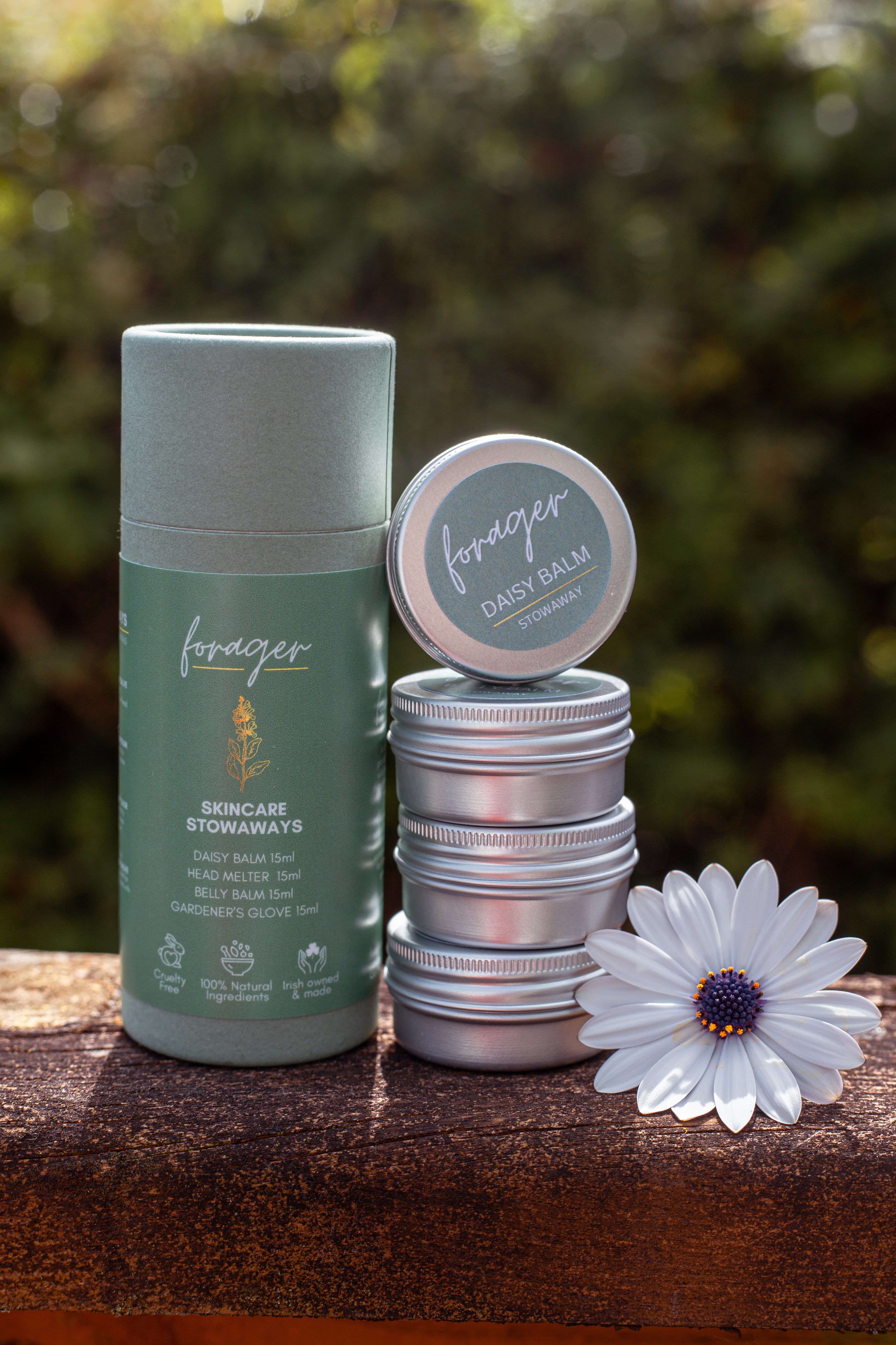Forager Skincare Stowaways set with Daisy Balm tins and a white flower on a wooden surface.