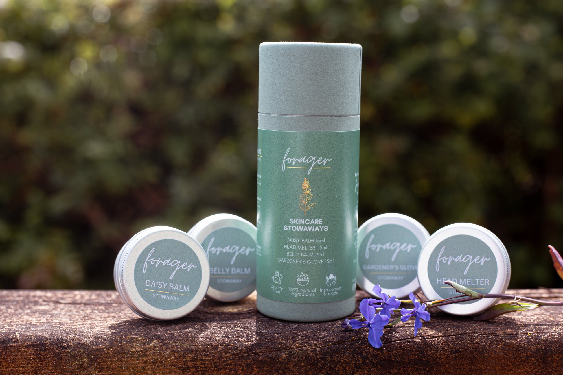 Forager Skincare Stowaways set featuring natural balms and a daisy flower on a wooden surface.