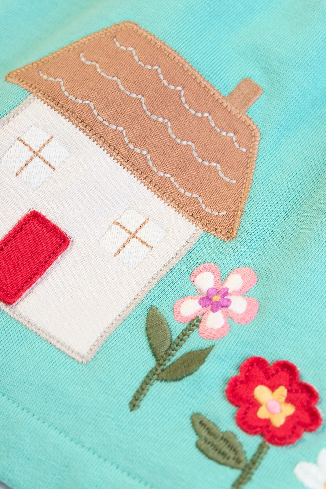 House and floral appliqué detail on the turquoise Frugi GOTS certified organic cotton dress, part of a baby girl outfit with a matching top, ideal as a baby gift.