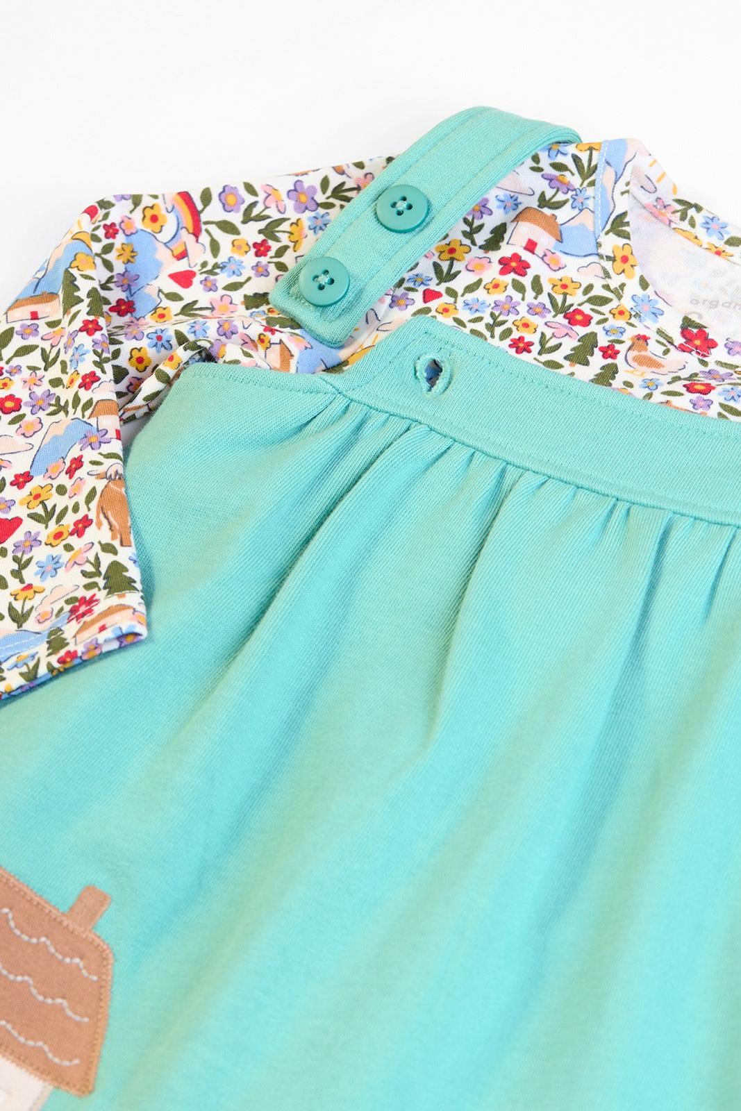 Close-up of the button straps and floral top on a Frugi baby girl outfit, with a turquoise GOTS certified organic cotton dress, a colourful baby gift.