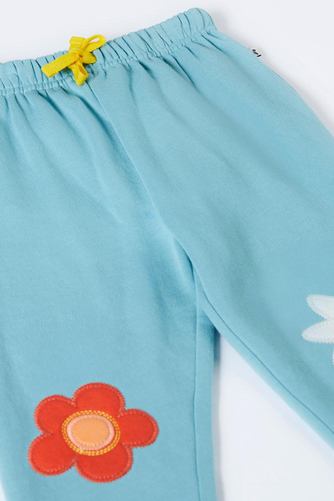 Light blue pants with a red flower design on a white background