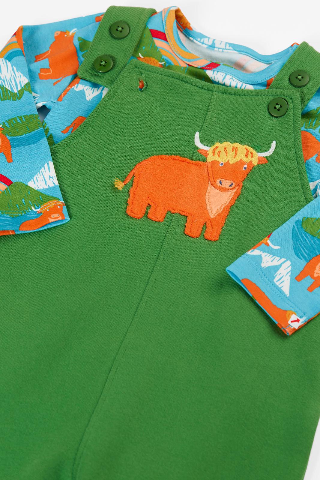 A close-up of a children's green overall-style romper or sleeper with a large orange bull applique on the chest, blue long sleeves with an orange animal print, and green snap closures at the shoulder.