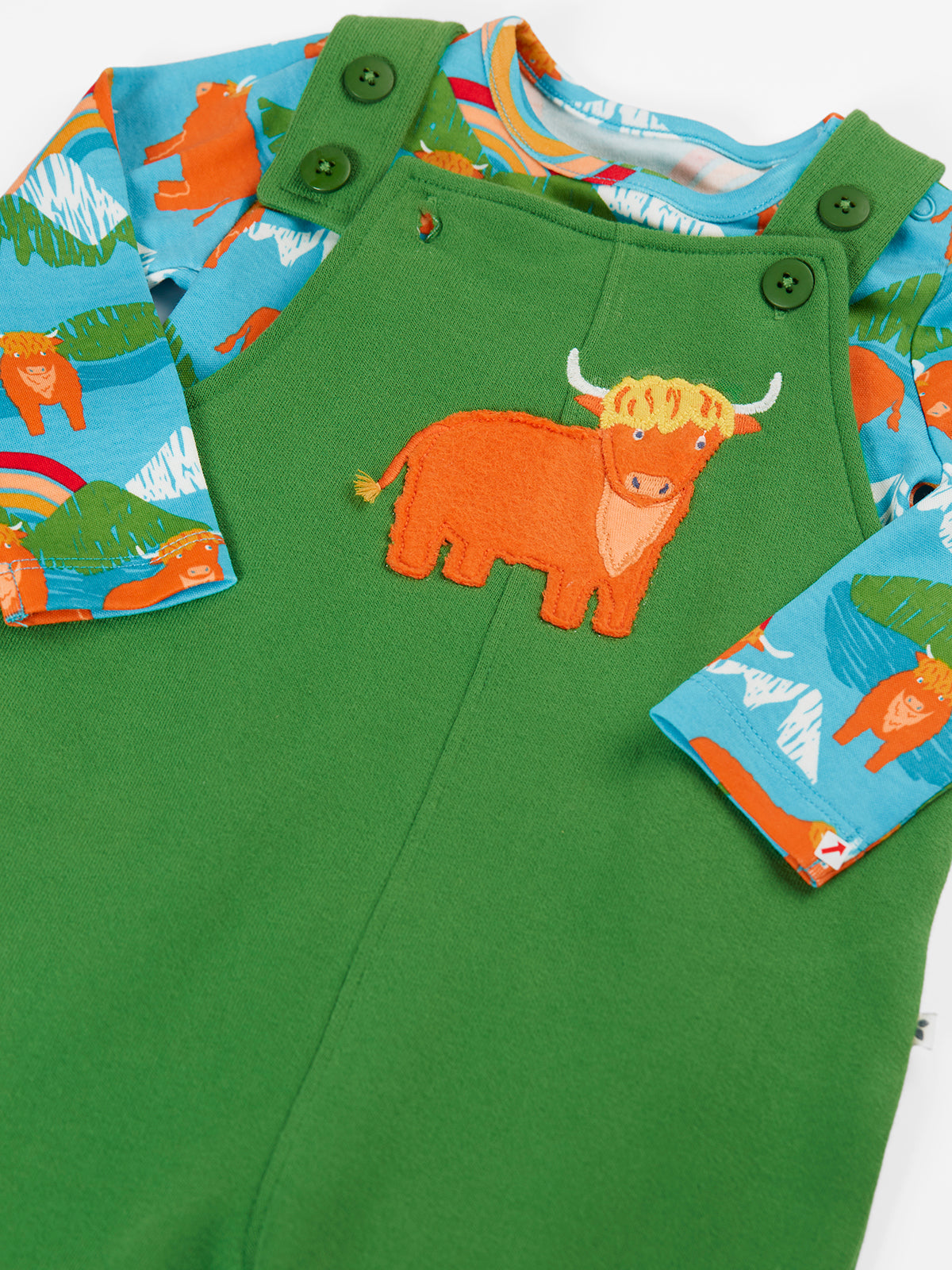 A close-up of a children's green overall-style romper or sleeper with a large orange bull applique on the chest, blue long sleeves with an orange animal print, and green snap closures at the shoulder.