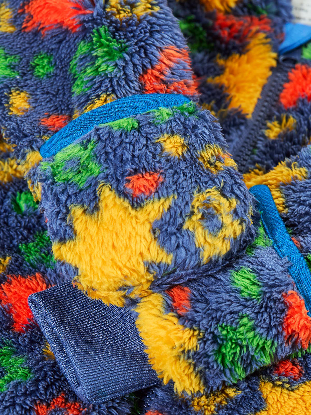 Close up of a colourful Frugi baby pramsuit made from recycled polyester fleece.