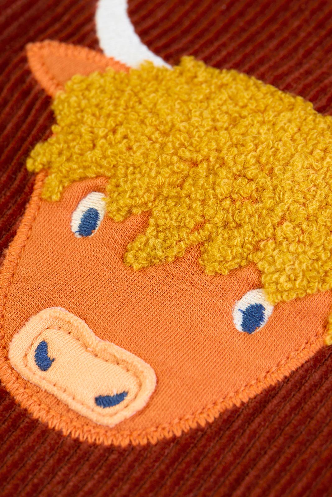 Close up of a Highland cow applique on brown Frugi organic cotton corduroy trousers.