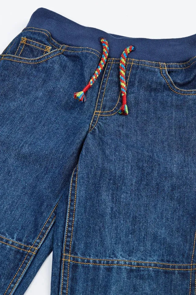 Frugi organic cotton kids jeans with a navy ribbed drawstring waist and multicolored braided ties.