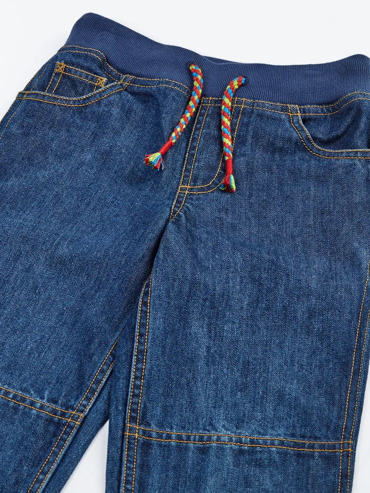 Frugi organic cotton kids jeans with a navy ribbed drawstring waist and multicolored braided ties.