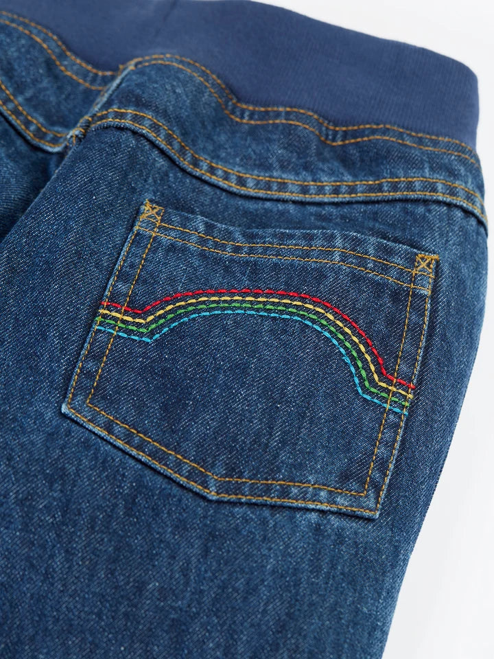 Close up of Frugi kids jeans pocket with rainbow stitching and blue elastic waistband.