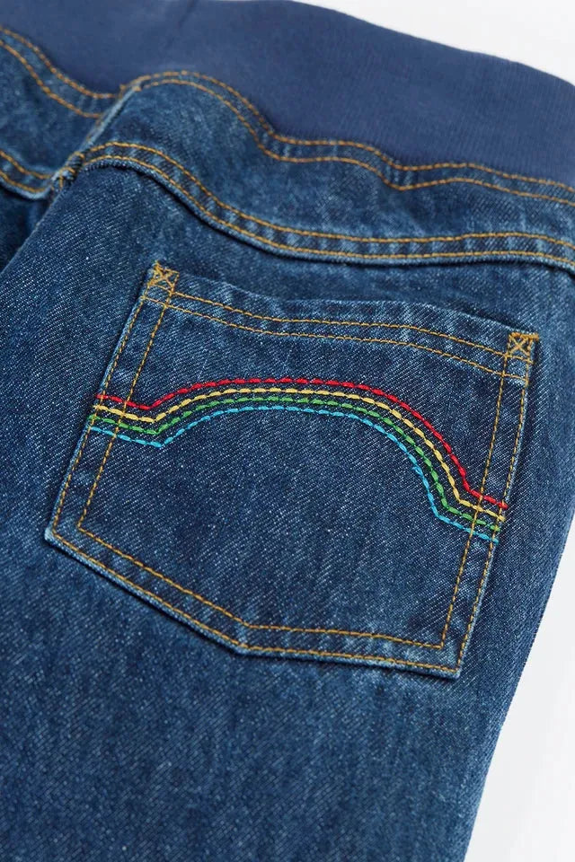 Close up of Frugi kids jeans pocket with rainbow stitching and blue elastic waistband.