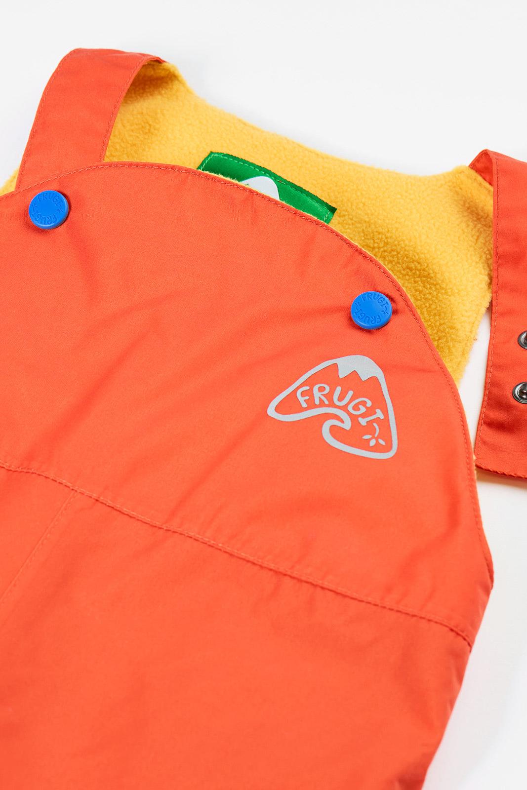 Close-up of Frugi orange dungarees featuring a fleece lining and reflective brand logo