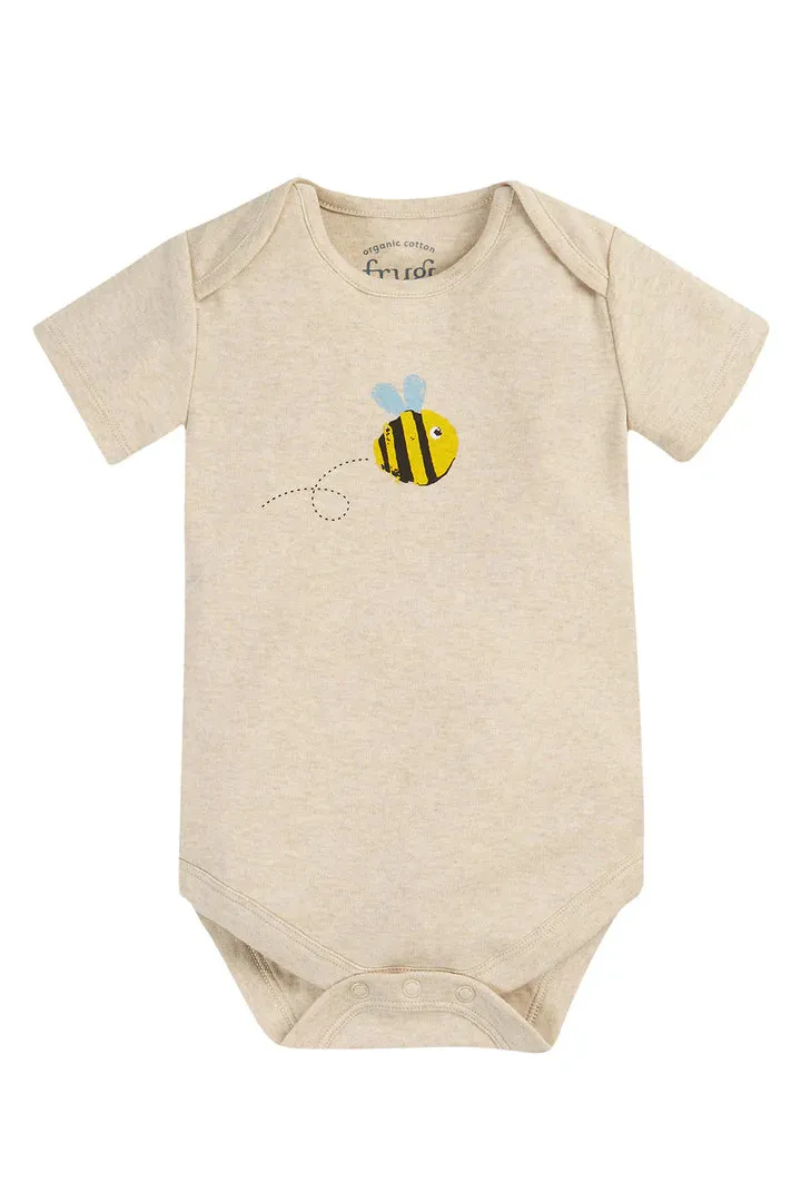 A short-sleeve baby bodysuit in a light heathered cream color, featuring a cute yellow and black bumblebee graphic on the chest with light blue wings. The brand name 'Frugi' is visible printed inside the collar.