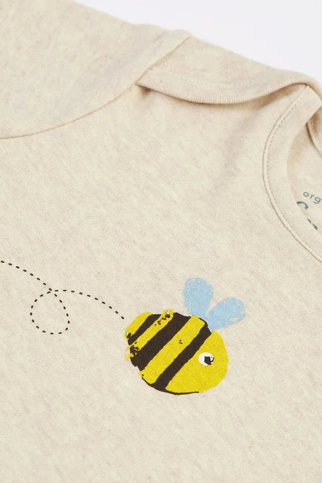 Close-up of a cream-colored organic cotton baby shirt featuring a cute bumblebee print and flight path detail