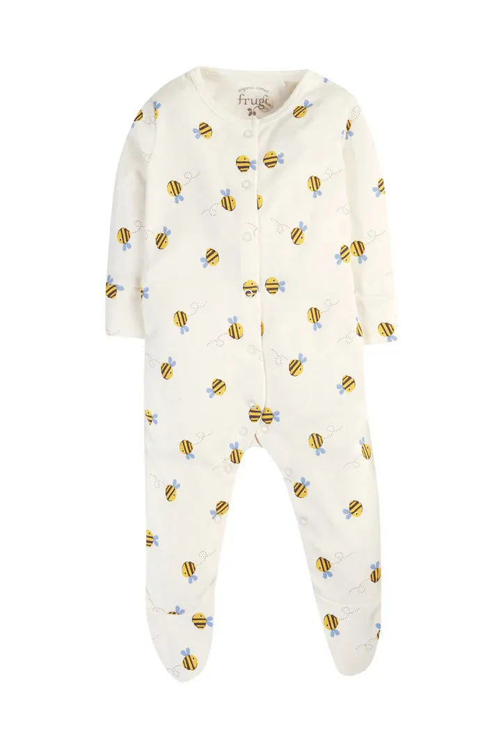 Cream colored Frugi baby sleepsuit featuring an all-over bumblebee pattern made from organic cotton