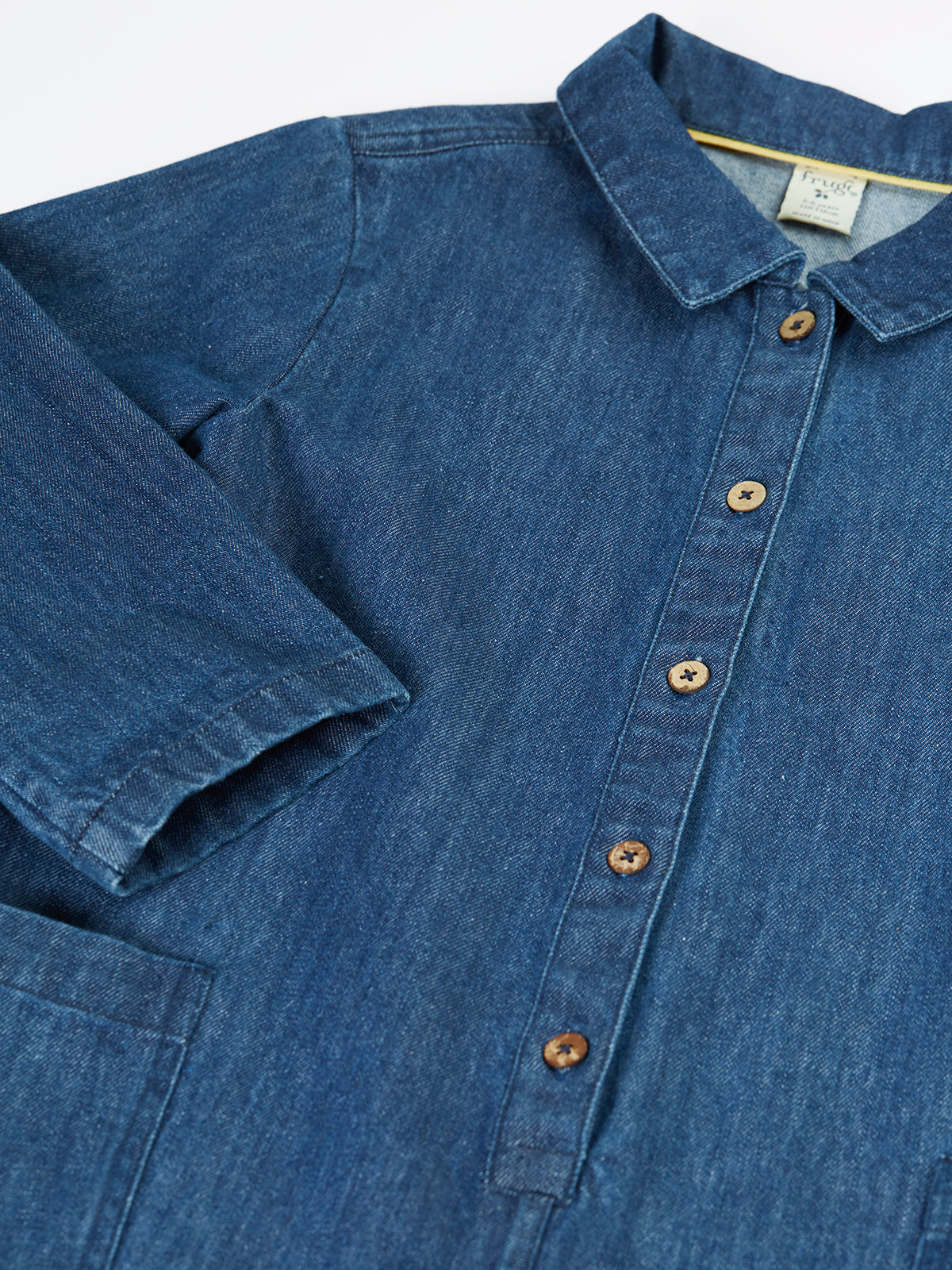 Close up of a blue Frugi organic cotton denim boiler suit with wooden buttons.