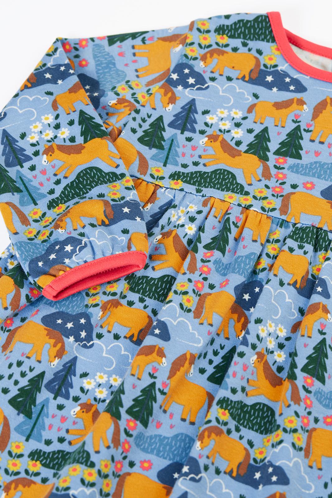 Frugi girls long-sleeve dress in blue organic cotton with a whimsical horse, tree, and flower pattern.