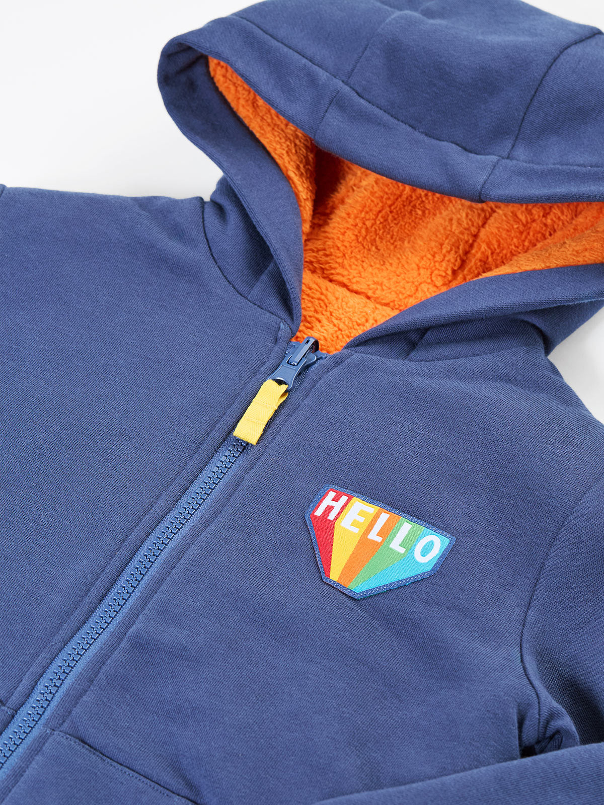A blue Frugi organic cotton hoody featuring a bright orange fleece lining and a colorful Hello rainbow patch.