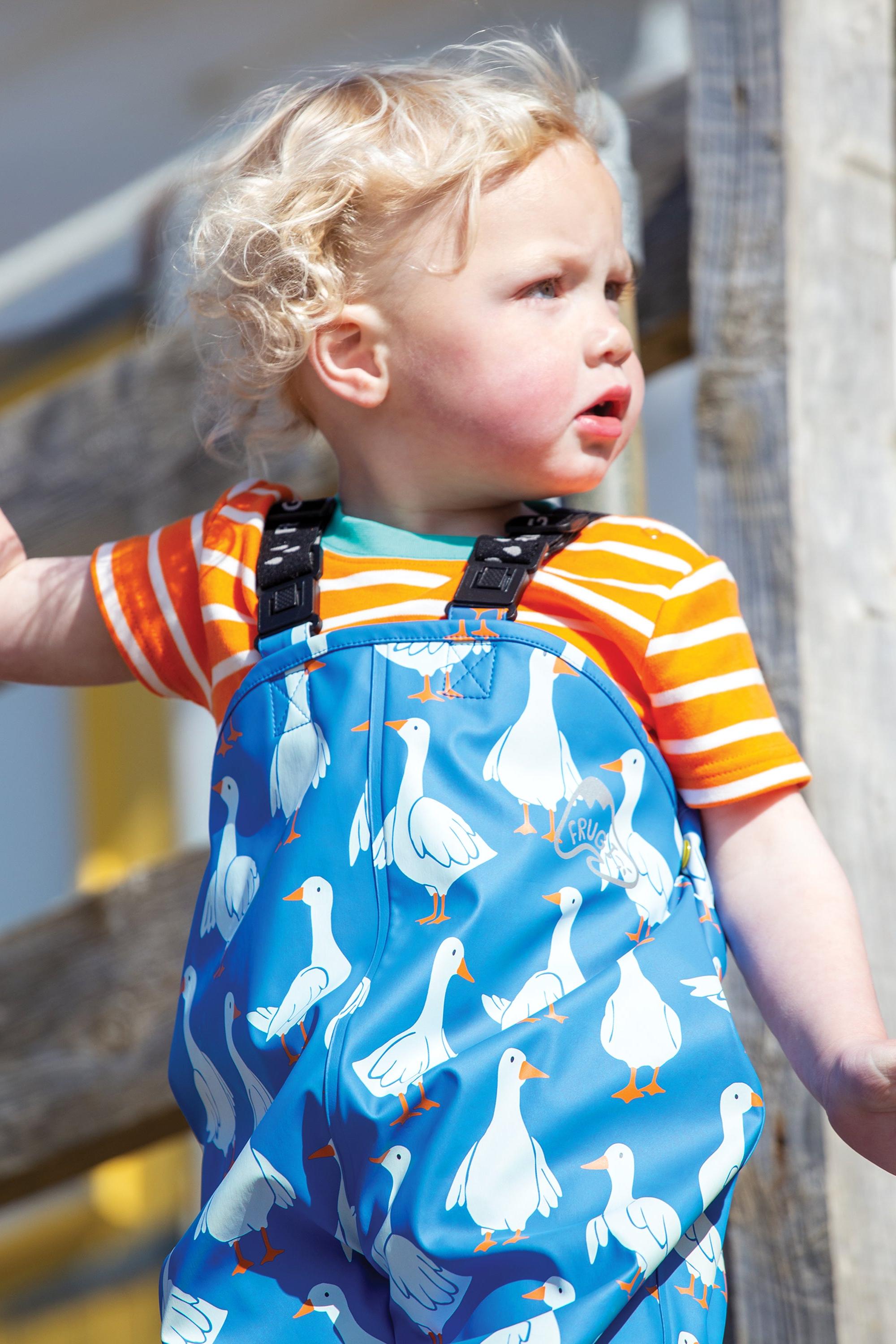 Child wearing blue rain trousers with goose pattern outdoors