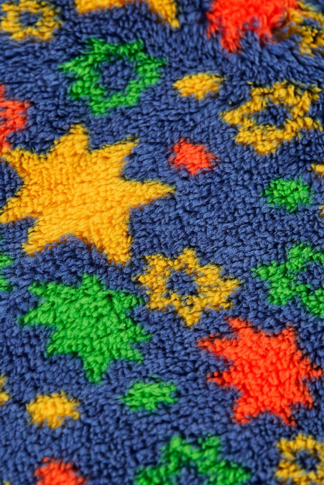 Close-up of a blue Frugi boys fleece fabric featuring a colourful star pattern.