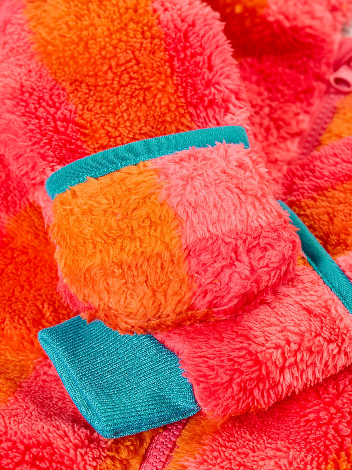 Close-up of a colourful Frugi baby snuggle suit made from recycled polyester fleece.
