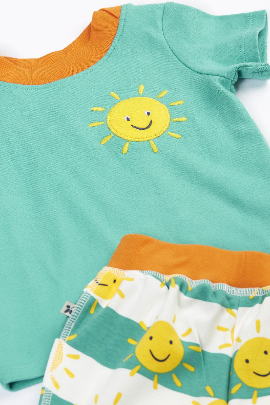 Frugi children's t-shirt and shorts set with a smiling sun pattern in green and orange.
