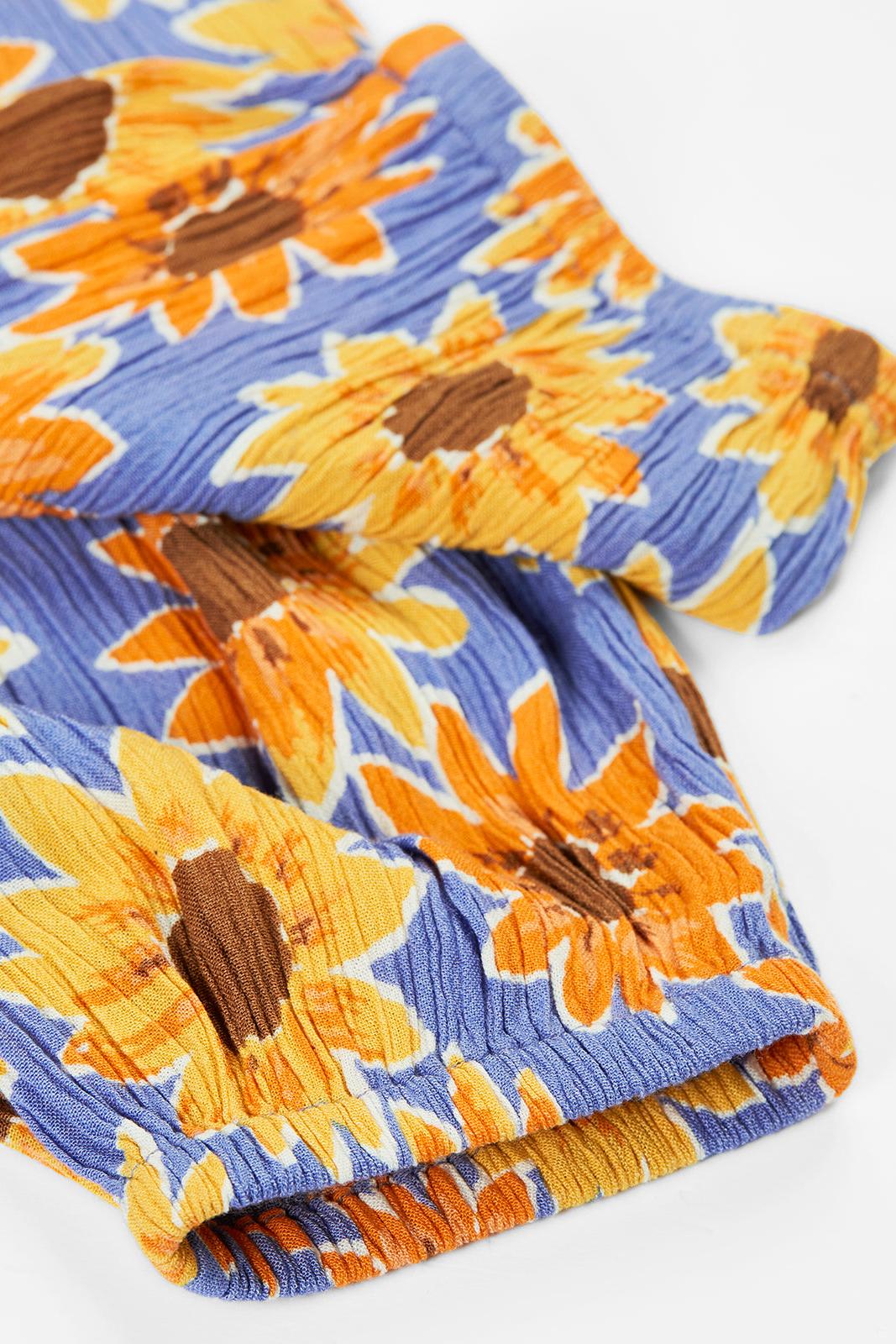 Close-up of Frugi fabric featuring a blue and yellow sunflower print with a textured, crinkled finish.