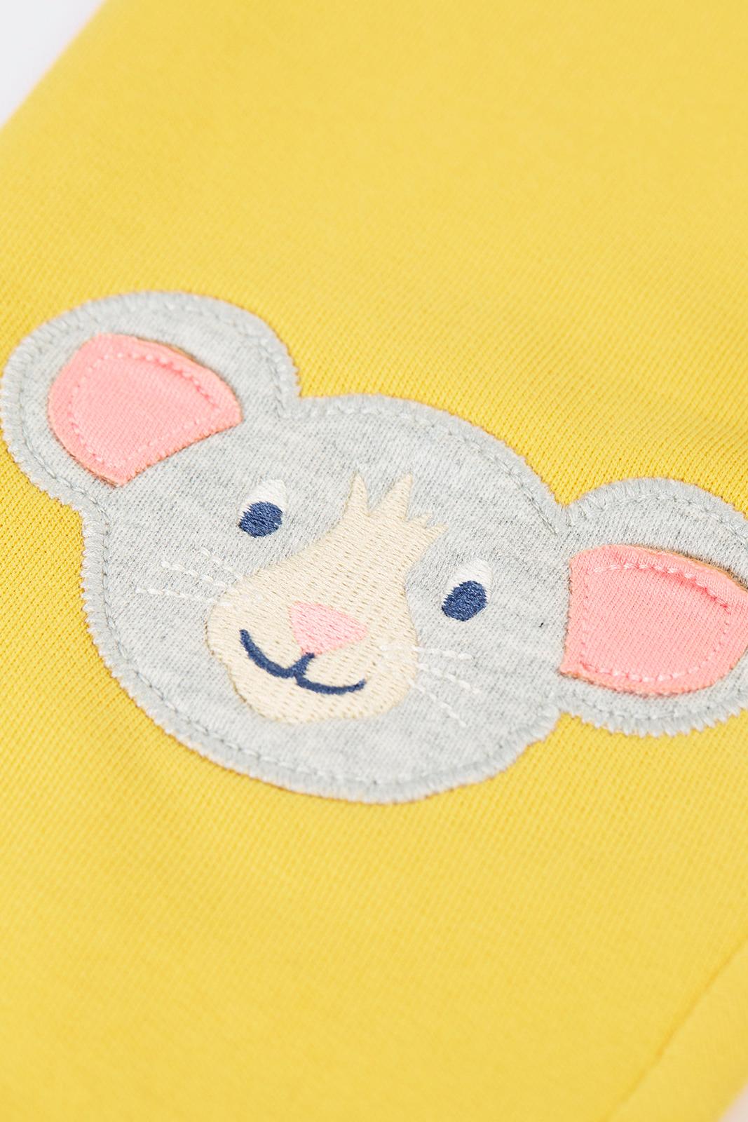 Close-up of a cute mouse applique on yellow organic cotton trousers.